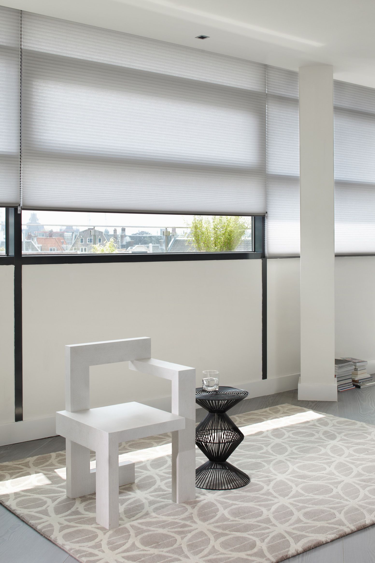 A white chair is sitting on a rug in front of a window in a living room.