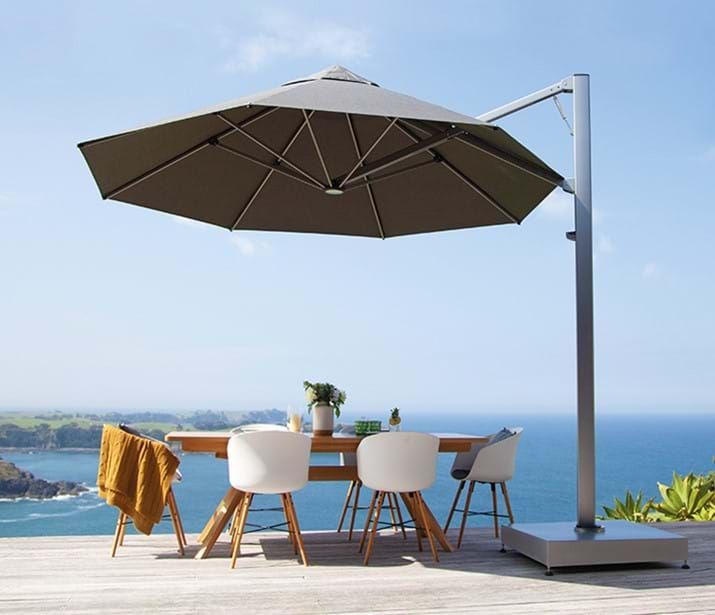 A table and chairs under an umbrella on a deck overlooking the ocean