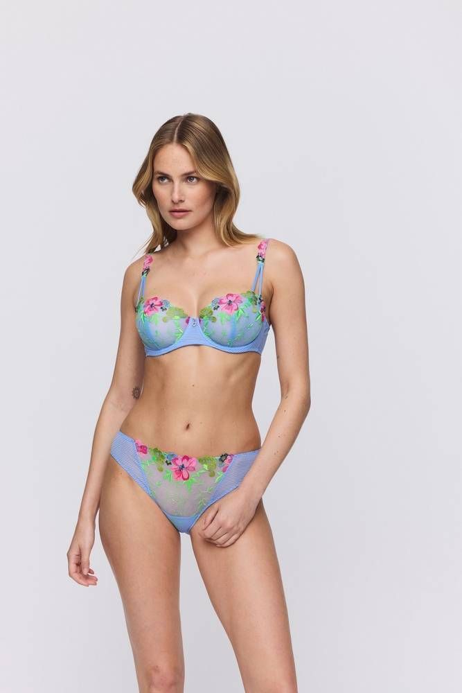 Une femme en lingerie se tient debout devant un fond blanc.