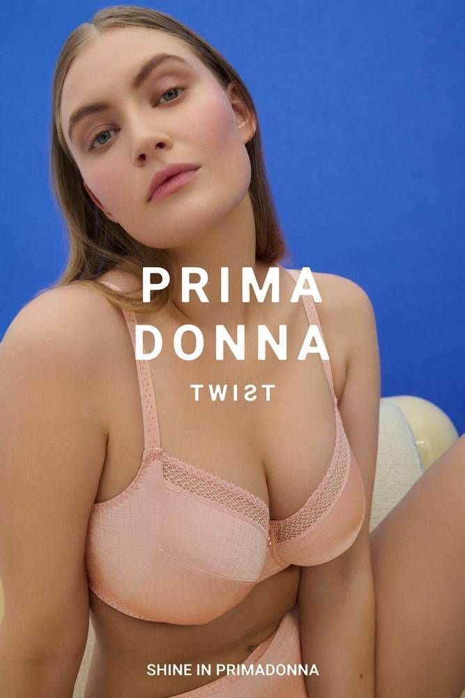 Une femme en soutien-gorge et sous-vêtements roses est assise sur un canapé.