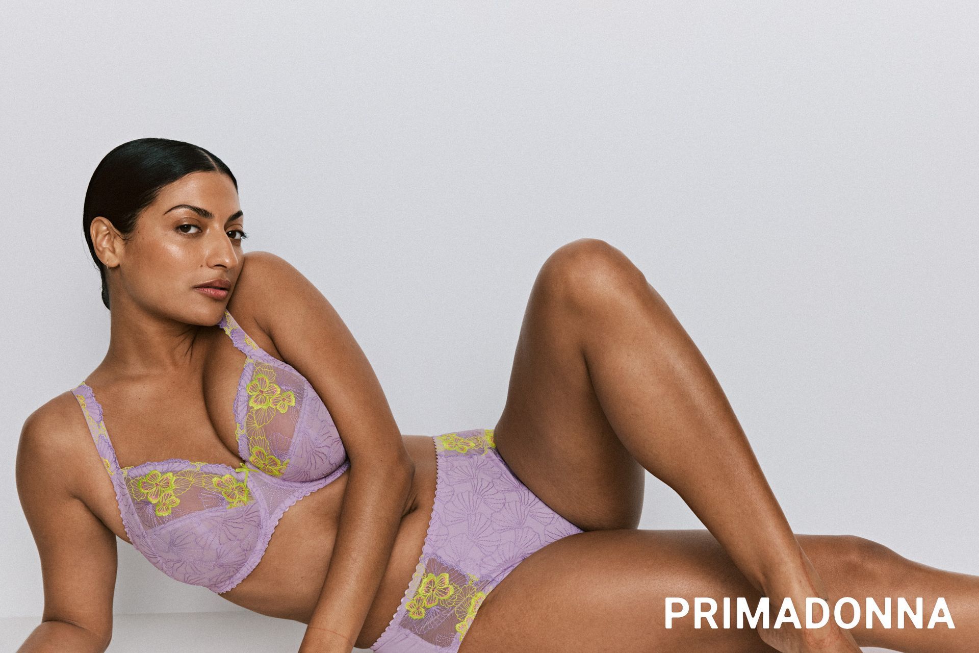 Femme portant de la lingerie lavande, posant sur fond blanc.