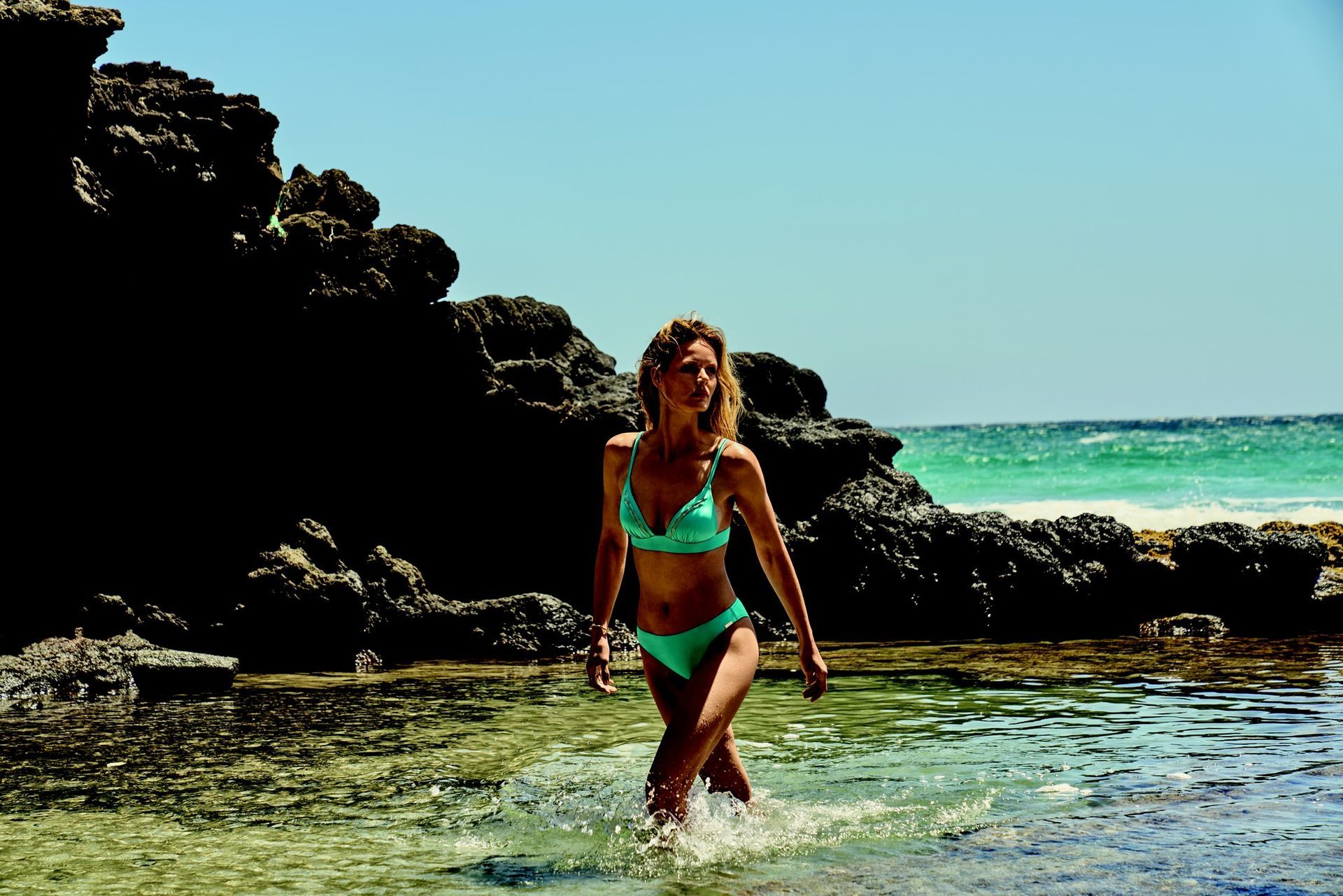 Une femme en maillot de bain blanc se tient à côté d'un bus avec un signe de paix peint dessus.