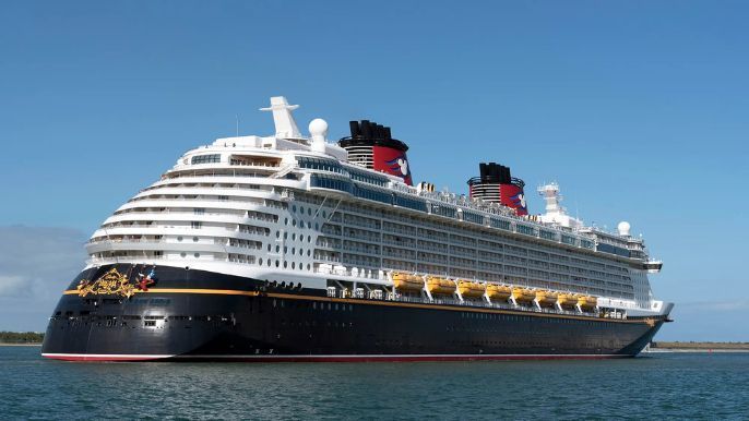 A large Disney cruise ship sailing on a sunny day.