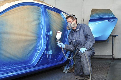 Worker painting a car using a paint spray gun