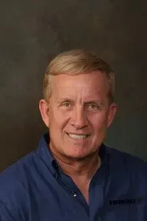 A man in a blue shirt is smiling for the camera.