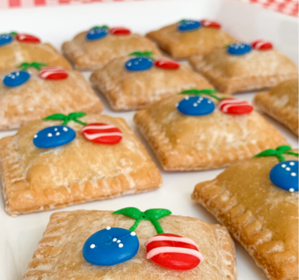 A bunch of pastries with red white and blue cherries on them