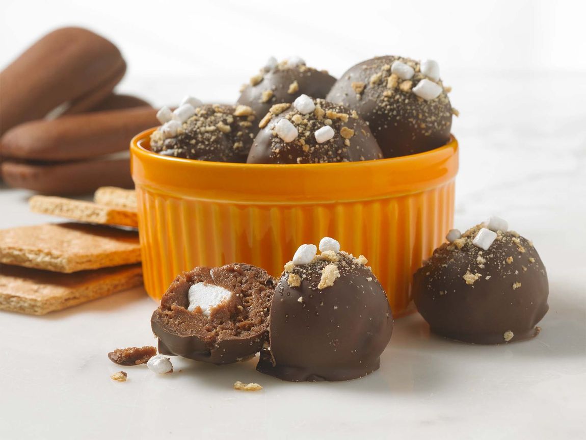 A yellow bowl filled with chocolate covered marshmallows and graham crackers.