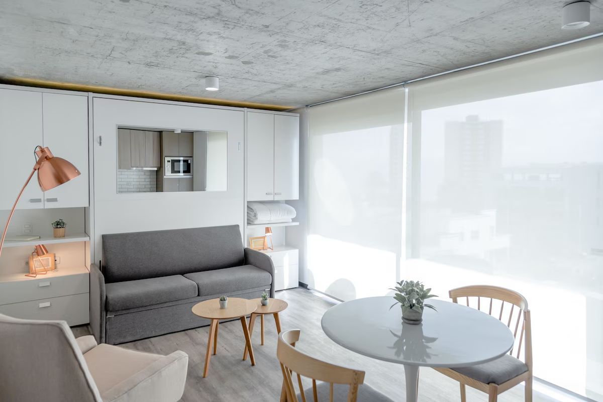 Interior de pequeño apartamento moderno con muebles blancos y grises.