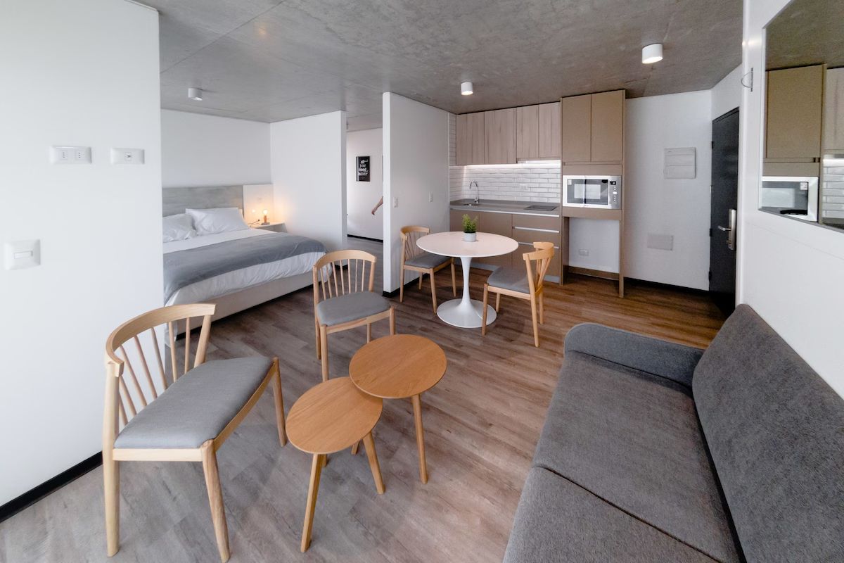 Moderno apartamento tipo estudio con cama, sofá, pequeña cocina y comedor.