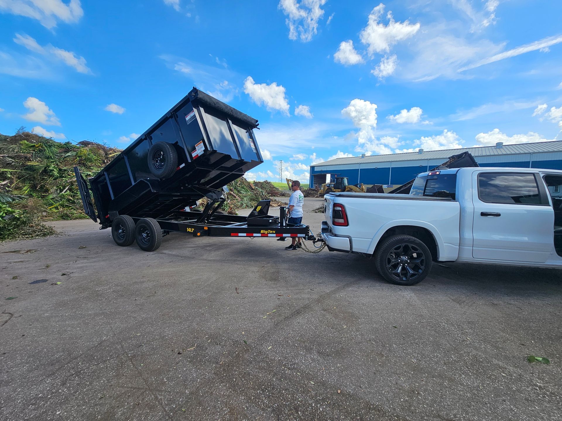 A white truck is towing a dumpster on a trailer.
