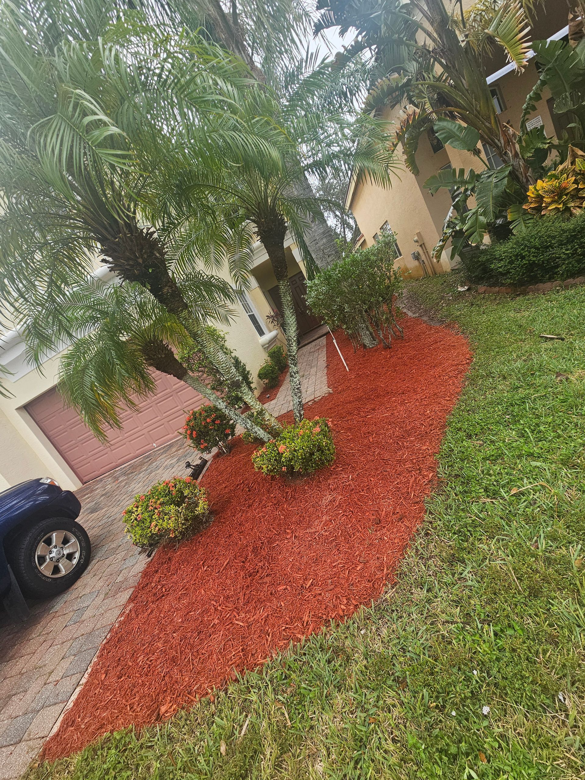 A jeep is parked in front of a house with a lot of mulch in the yard.