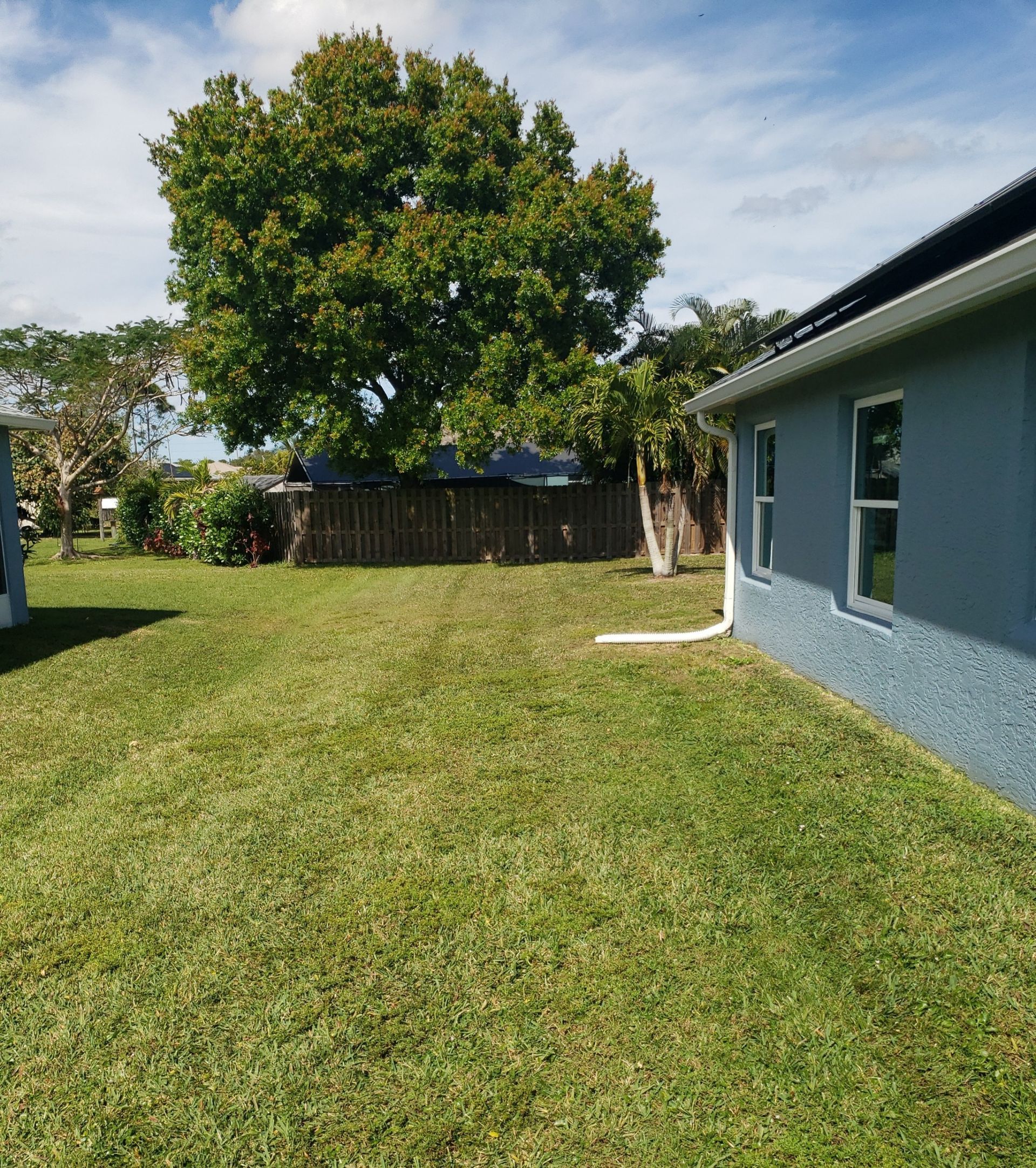 A blue house with a large lawn in front of it.