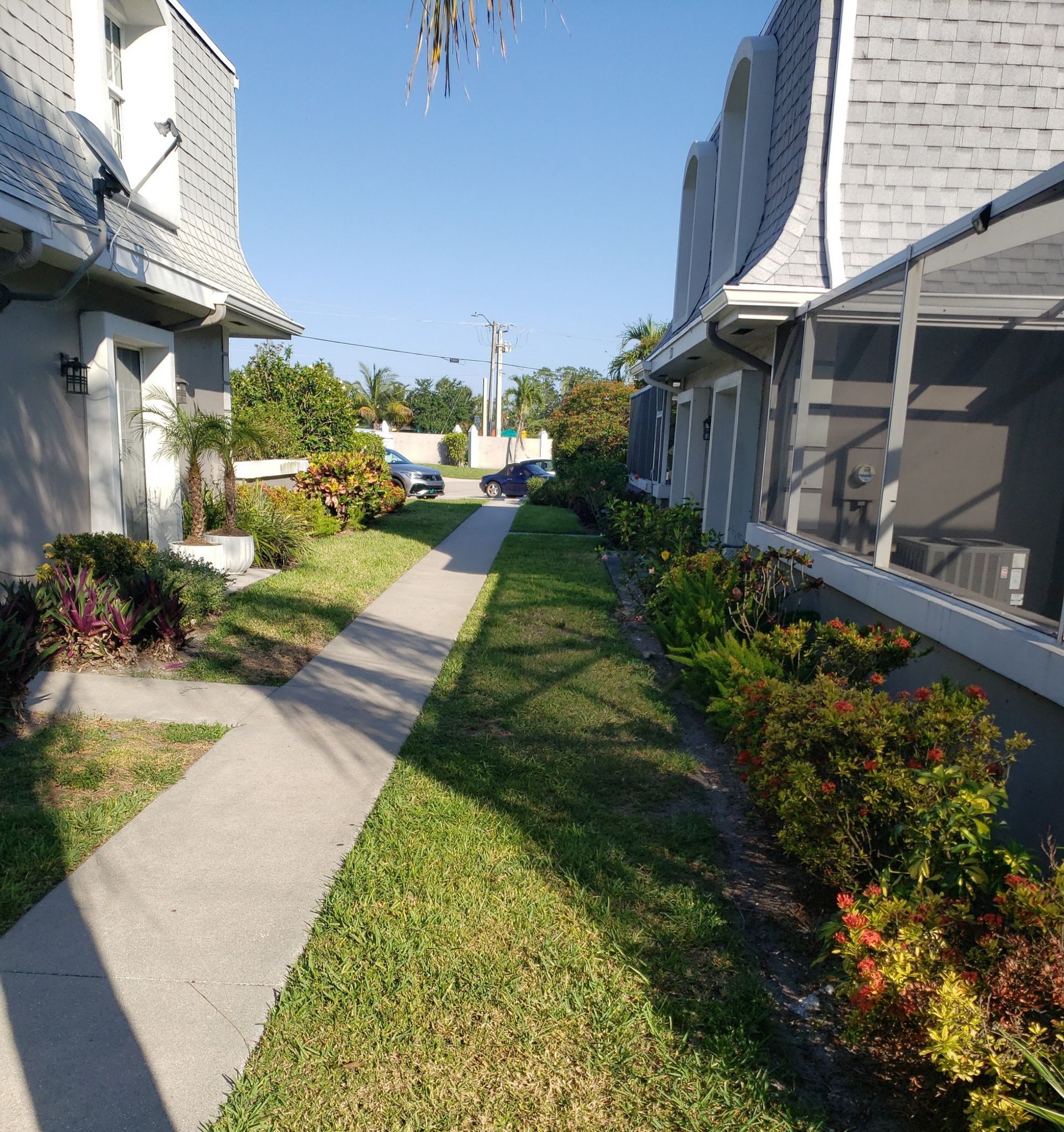 A walkway between two houses with a satellite dish on the side