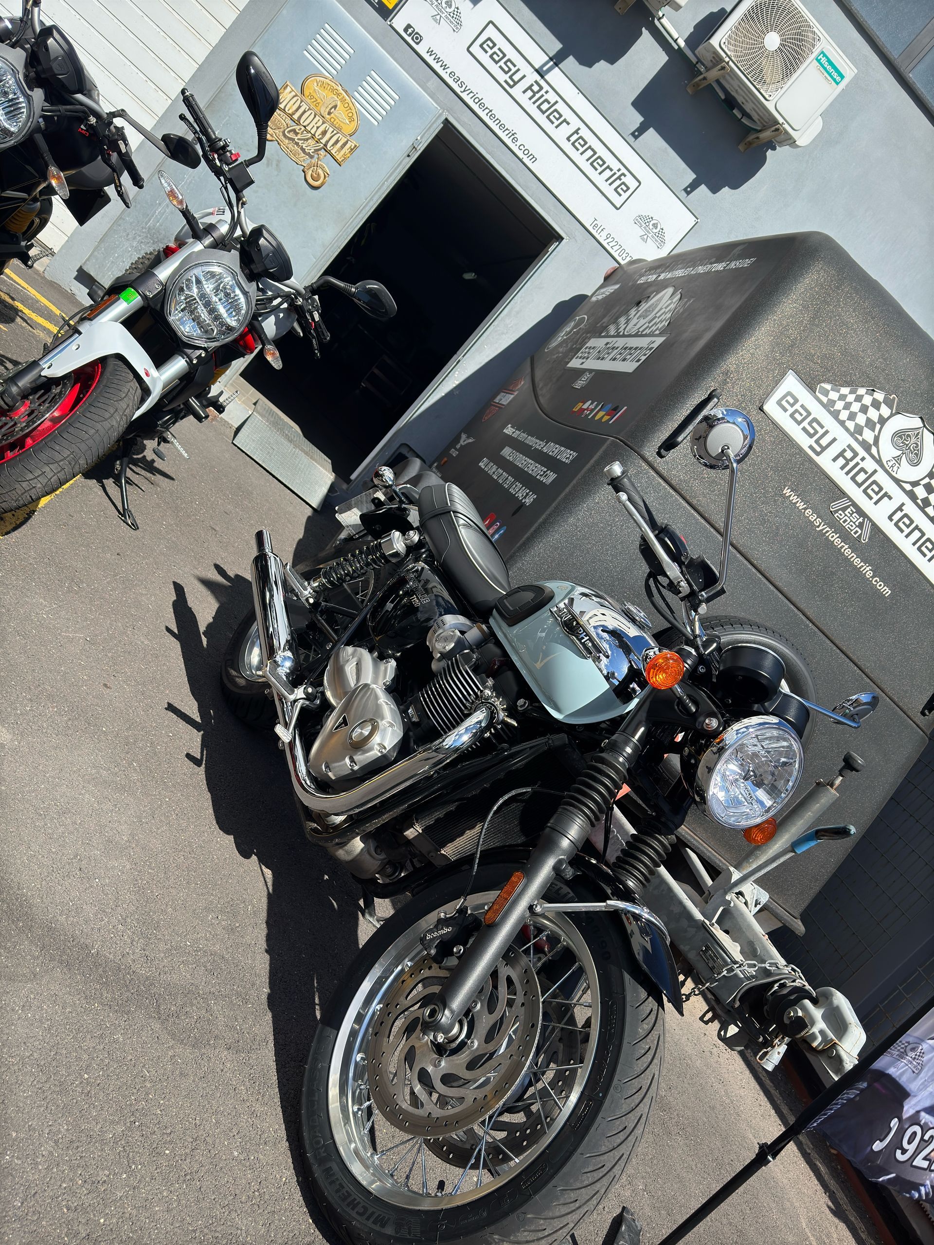 Two motorcycles are parked in front of a building.