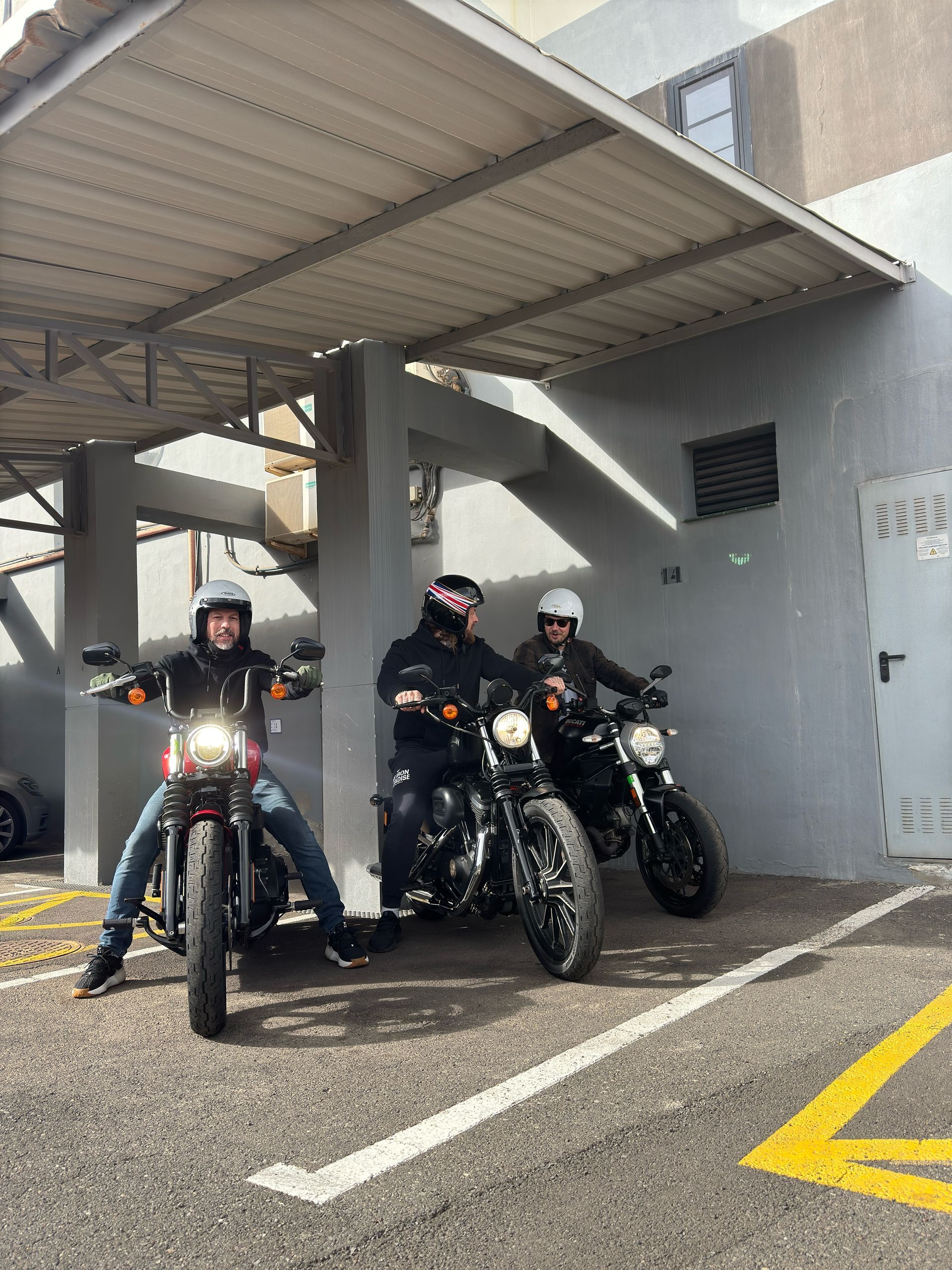 Three people are riding motorcycles in a parking lot
