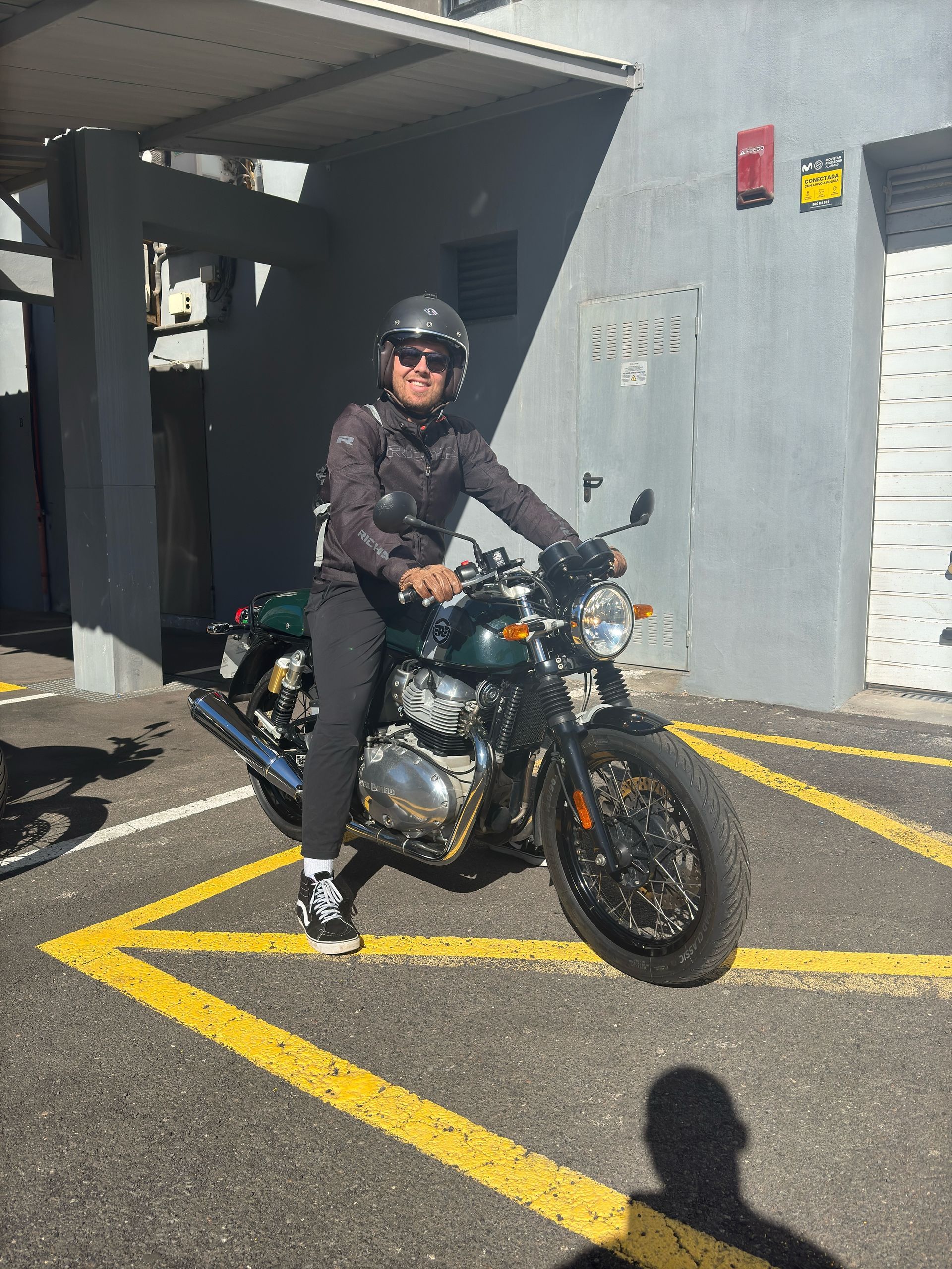 A man is riding a motorcycle in a parking lot.