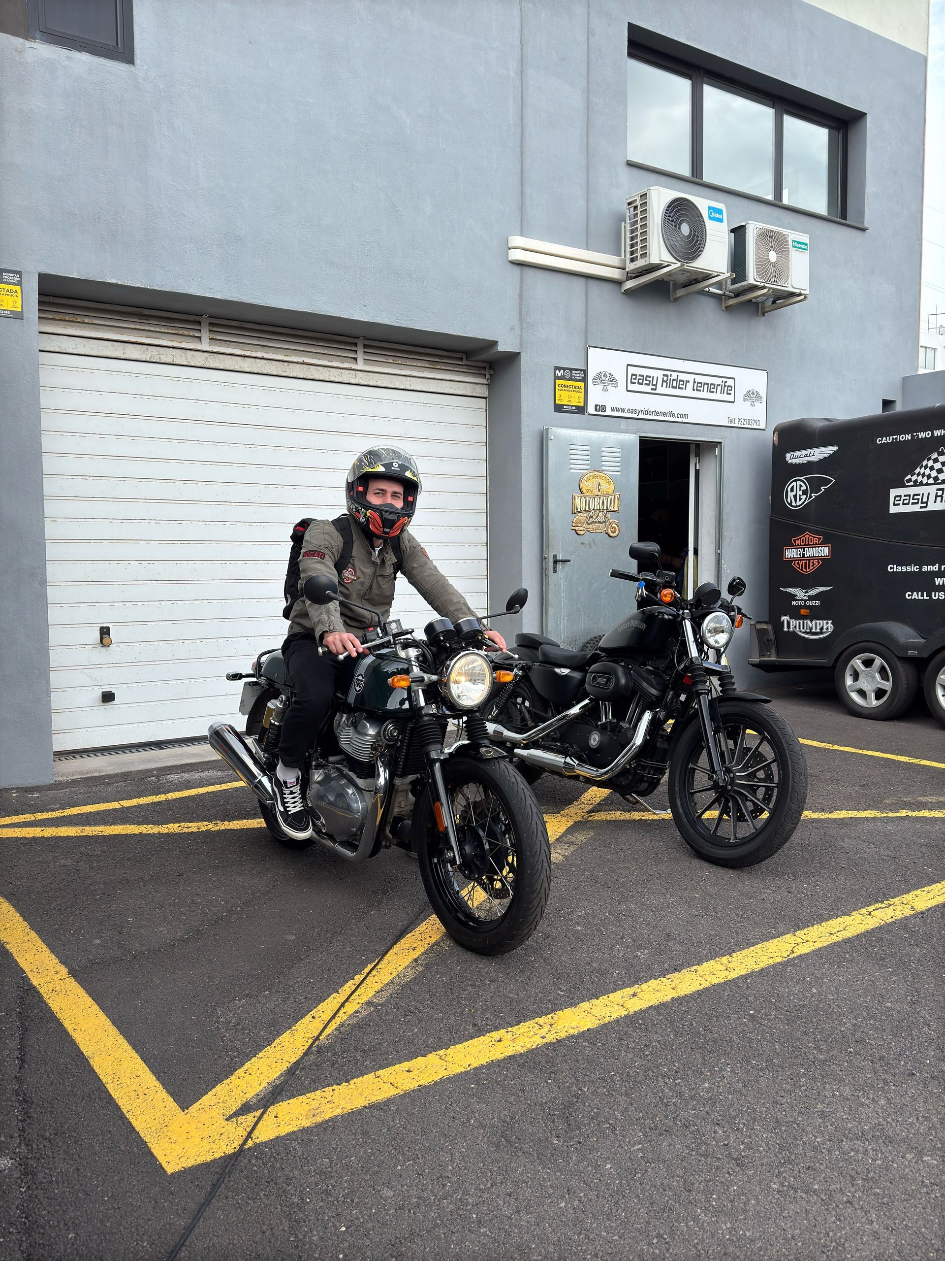 A man is riding a motorcycle in a parking lot.