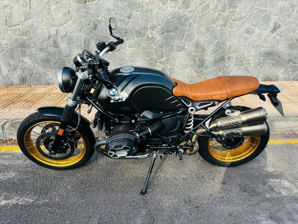 A black motorcycle with a brown seat is parked on the side of the road.