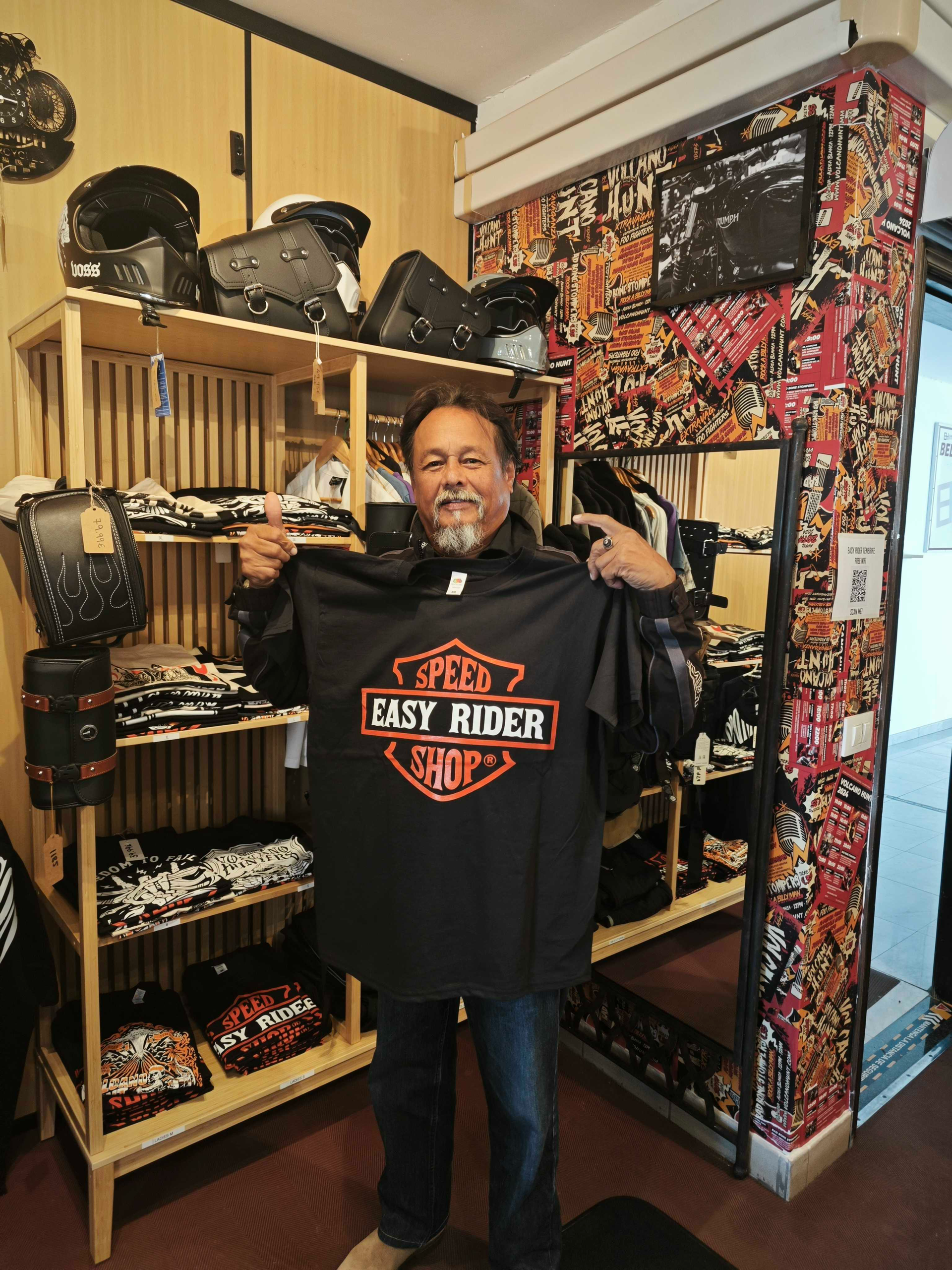 A man is holding up a harley davidson shirt