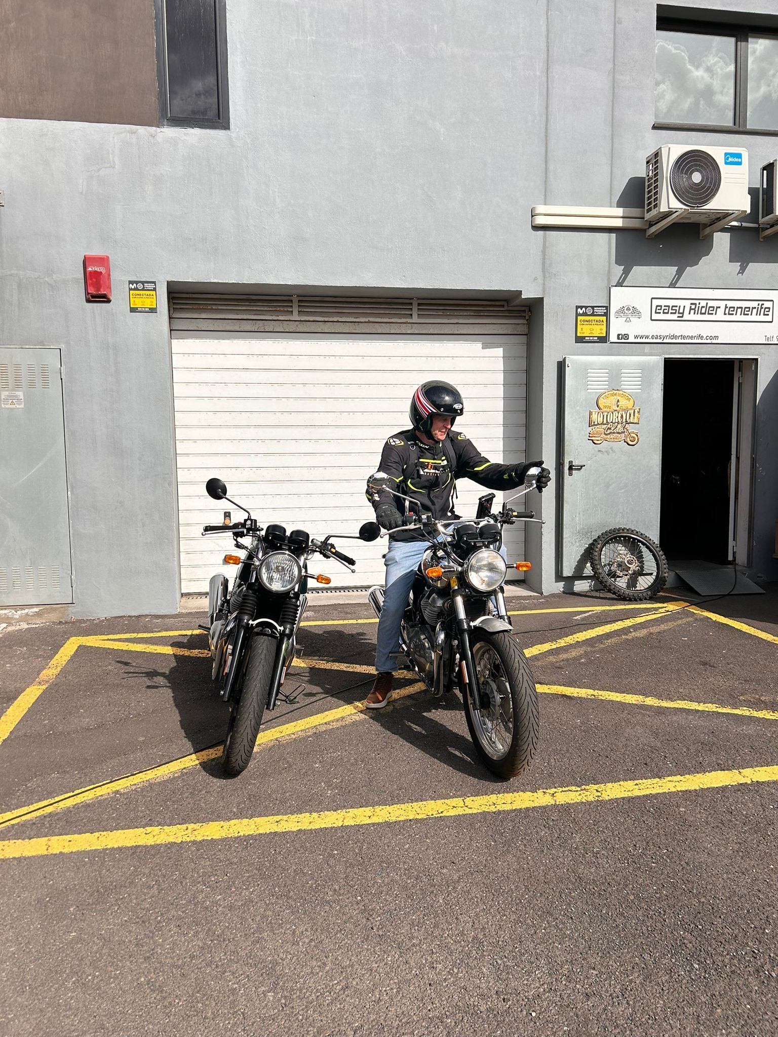 A man is standing next to two motorcycles in a parking lot