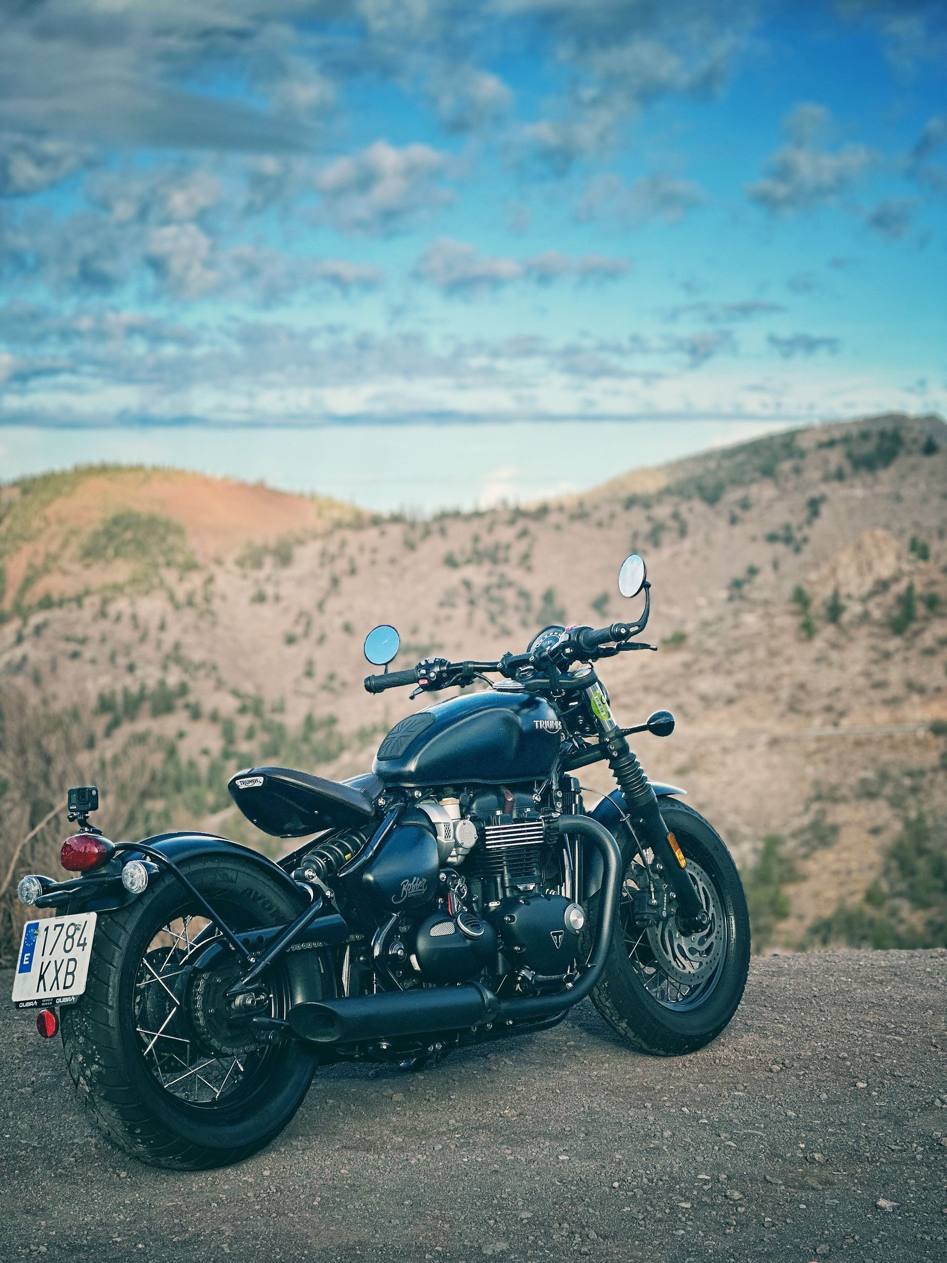 A black motorcycle is parked on top of a dirt hill.