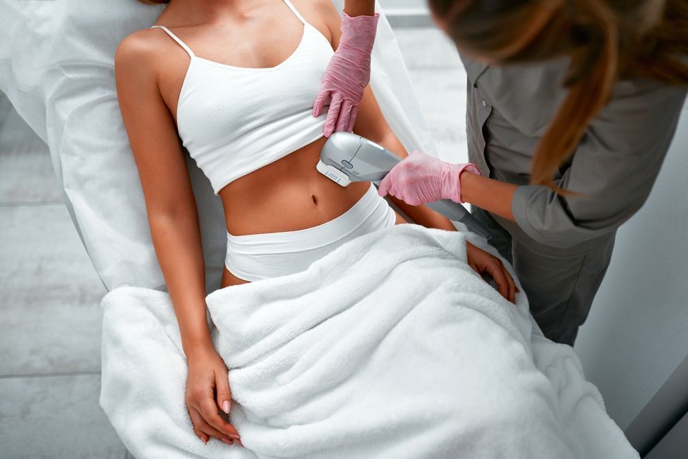 A woman is getting a laser treatment on her stomach.