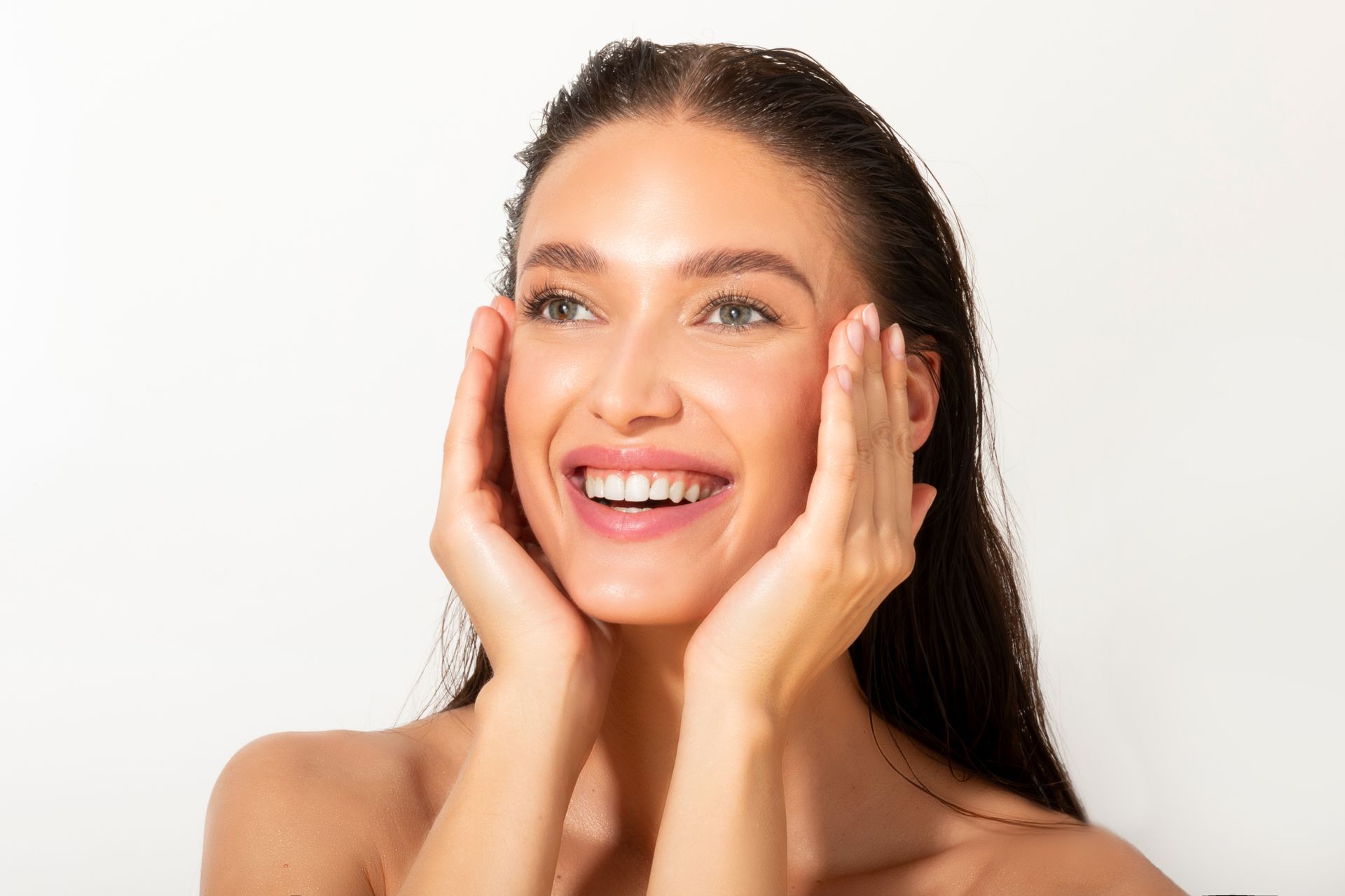 Smiling woman touching her cheeks against a white background