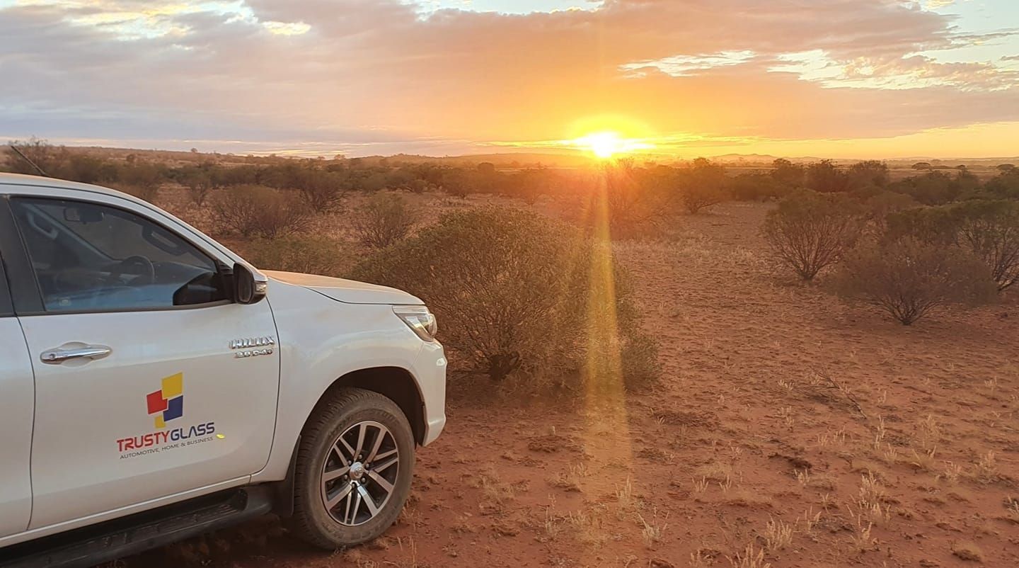 A White Truck is Parked in the Middle of a Desert at Sunset— Trusty Glass In Alice Springs, NT
