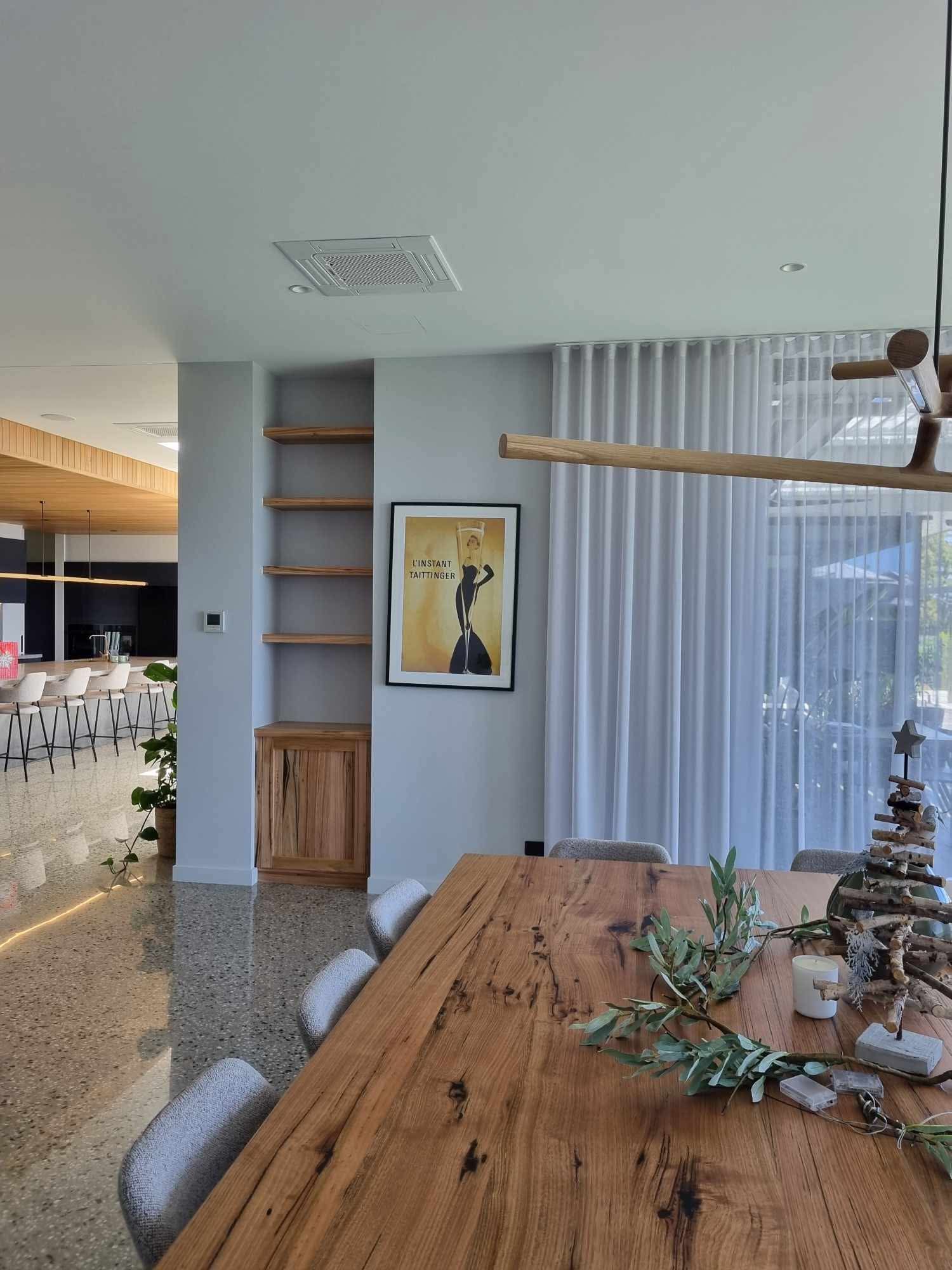 A dining room with a wooden table and chairs and a painting on the wall. 