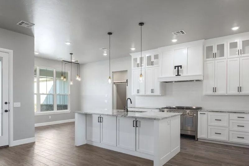 A kitchen with white cabinets , stainless steel appliances , and a large island.