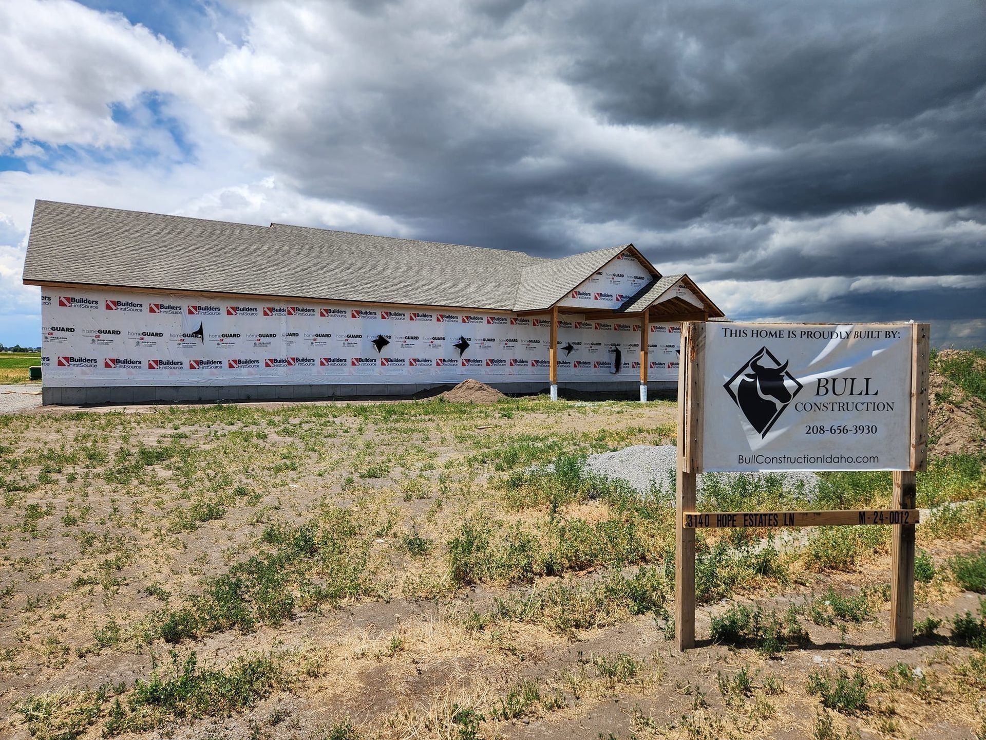 A house is being built in a field with a sign in front of it.