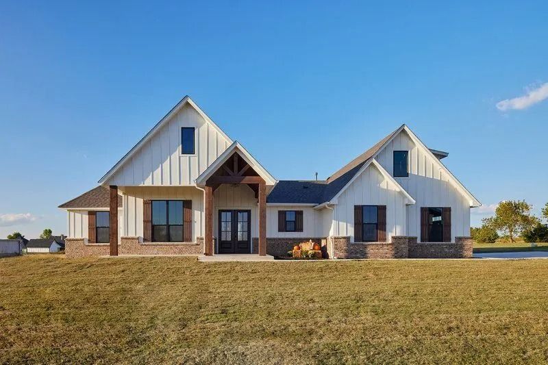 A large white house is sitting in the middle of a grassy field.