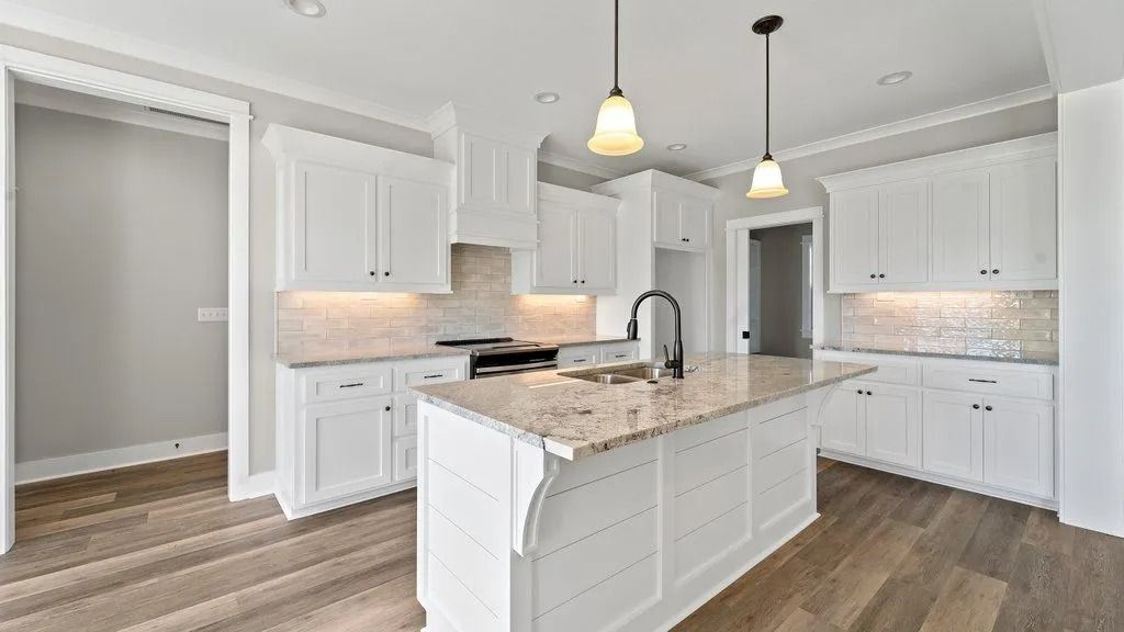 A kitchen with white cabinets , granite counter tops , and hardwood floors.