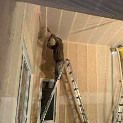 A man is standing on a ladder in a room.