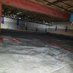 A basement with a lot of insulation and a tarp on the floor.