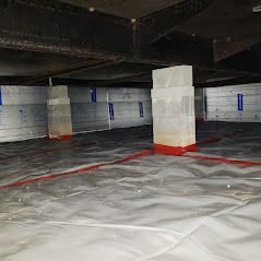 A large room with a lot of columns and a white tarp on the floor.