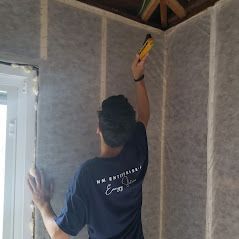 A man is measuring a wall with a tape measure.