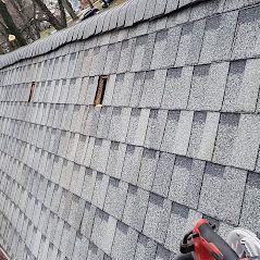 A person is standing on top of a roof with a tool on it.