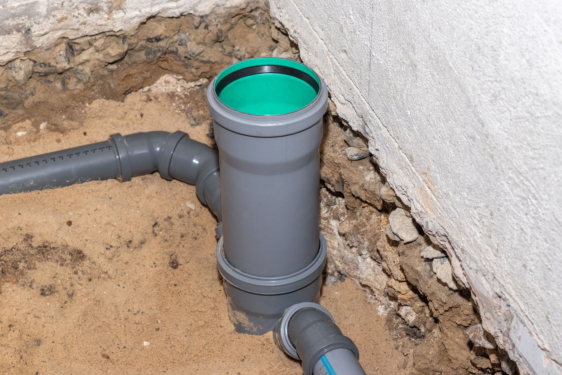 a drain pipe is being installed in the dirt next to a wall .