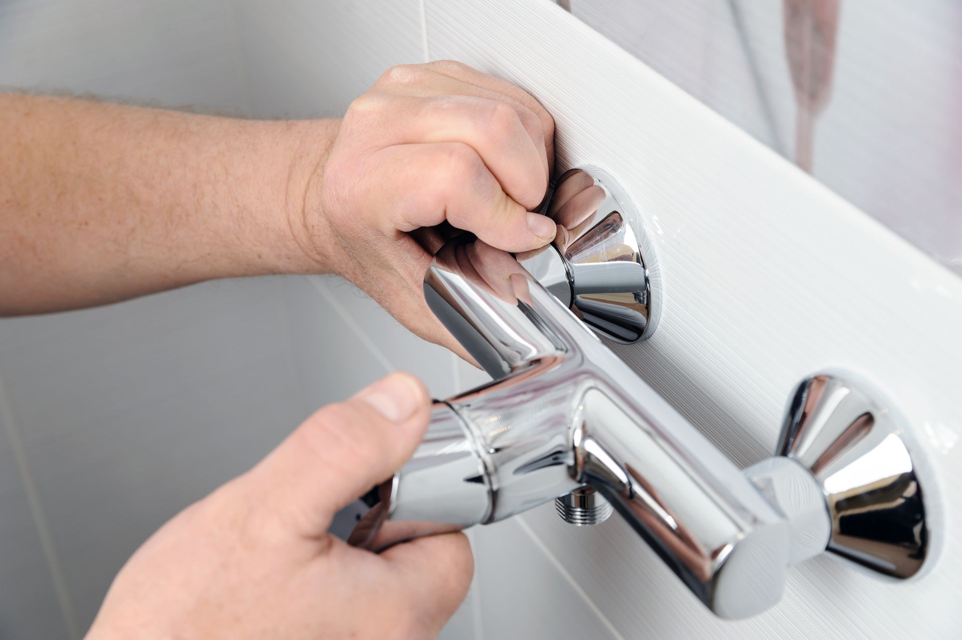 a person is fixing a shower head in a bathroom .