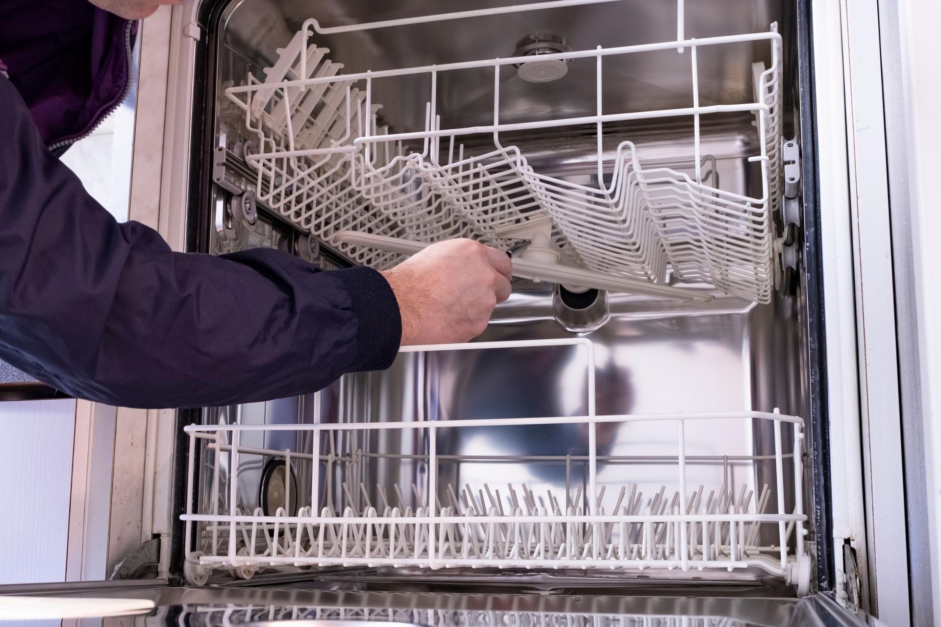 Person loading a dishwasher with cutlery baskets.