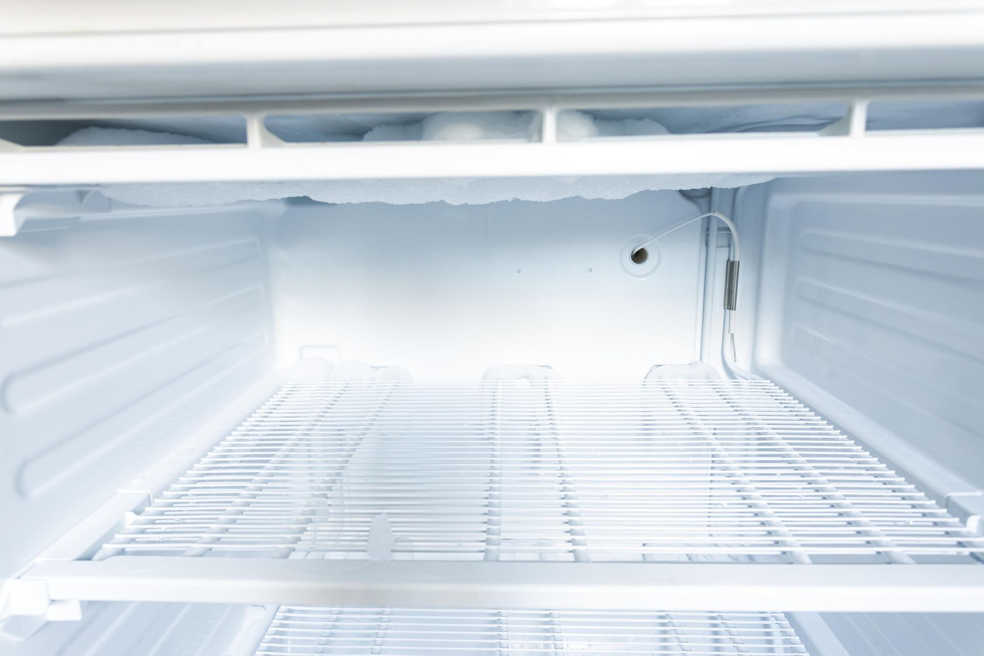 Empty, white refrigerator interior with wire shelving.