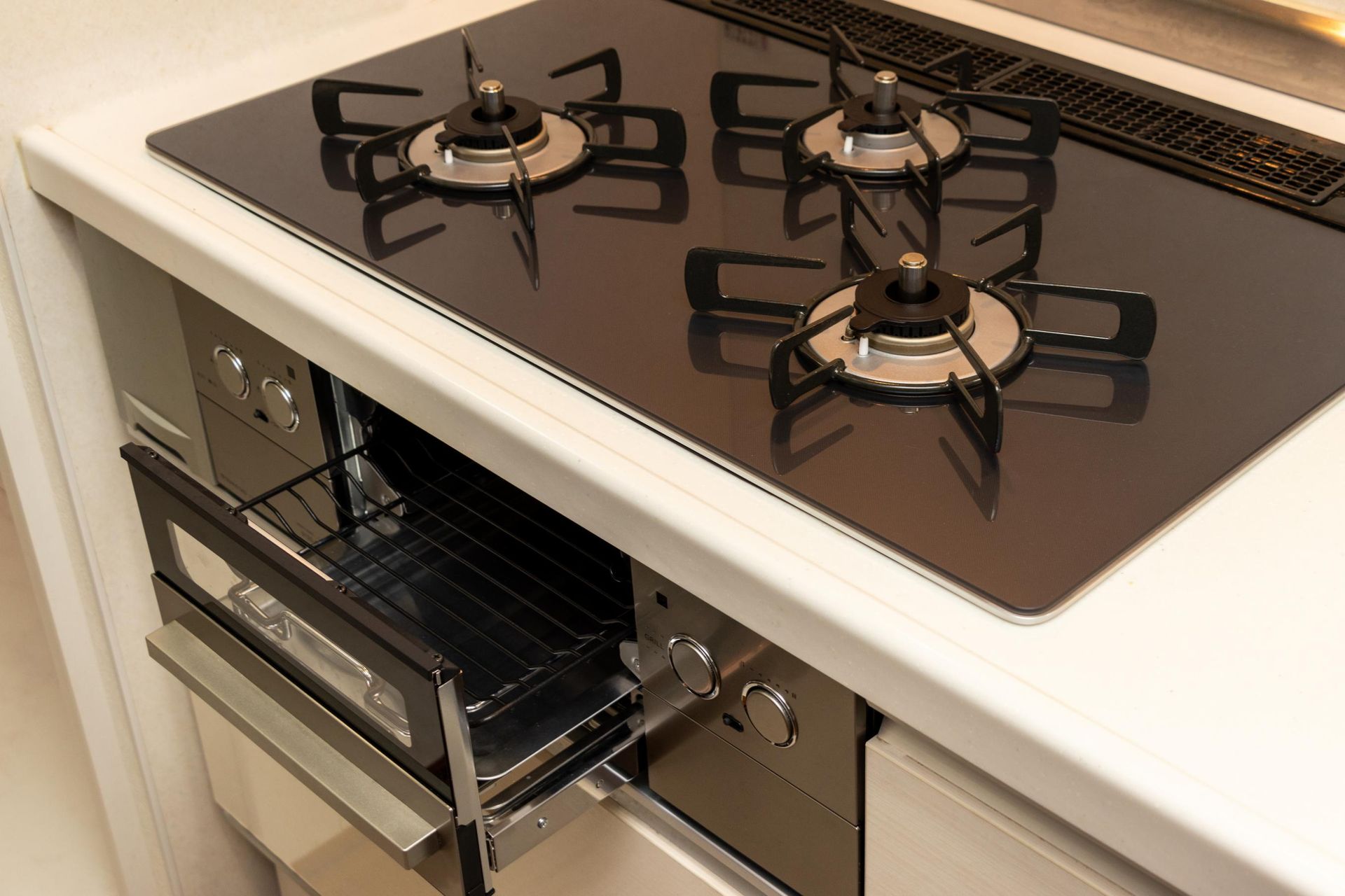 A modern kitchen stovetop with four burners and a pull-out oven below.