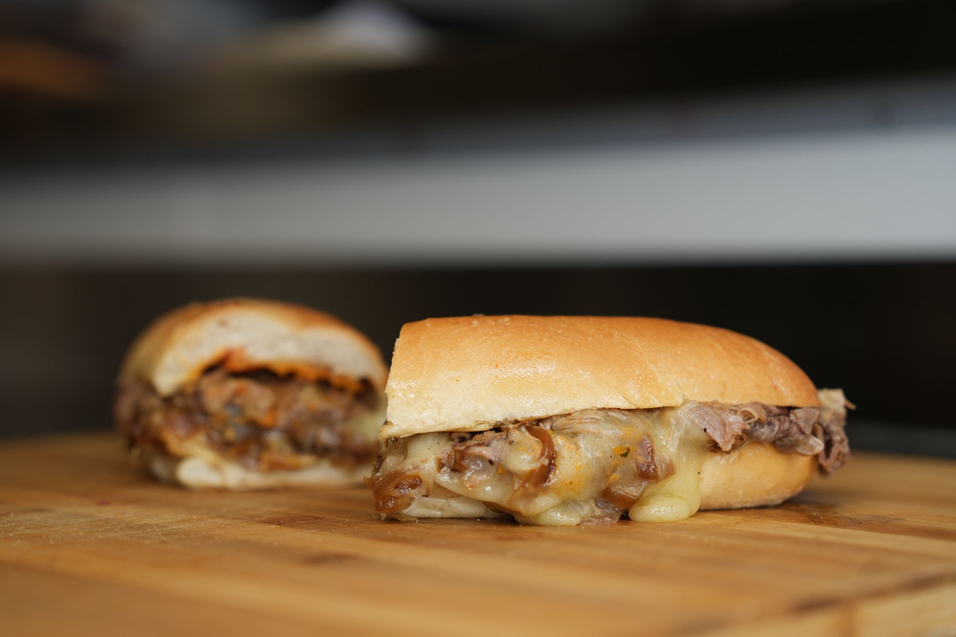 Two sandwiches are sitting on a wooden cutting board.