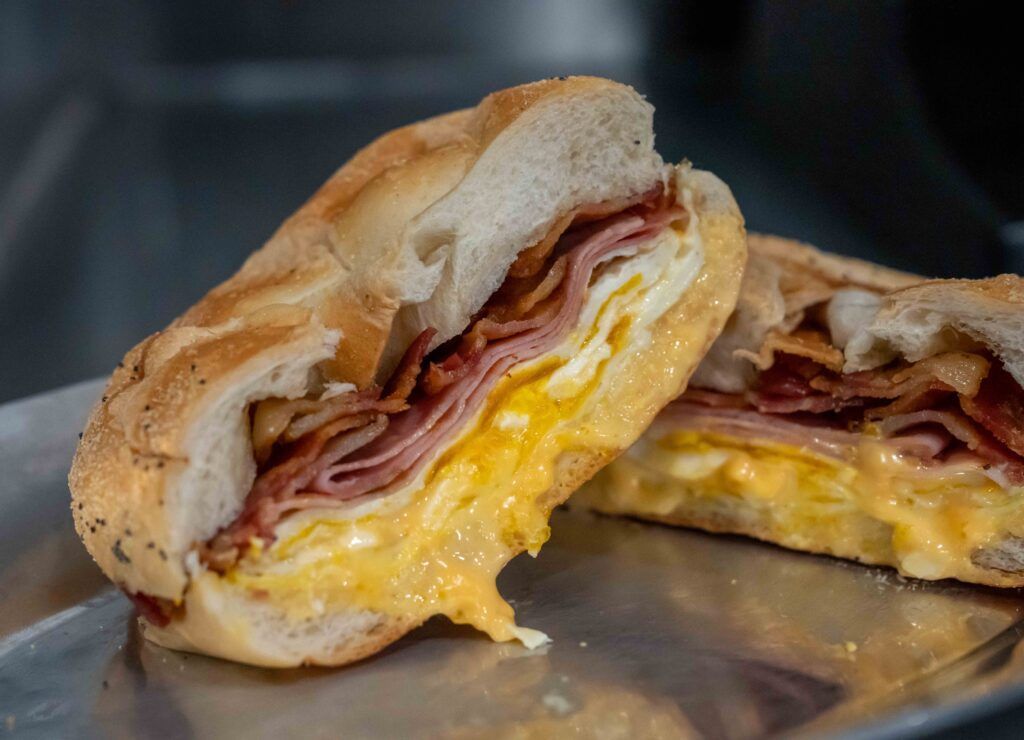 A sandwich with ham , egg , cheese and bacon on a plate.