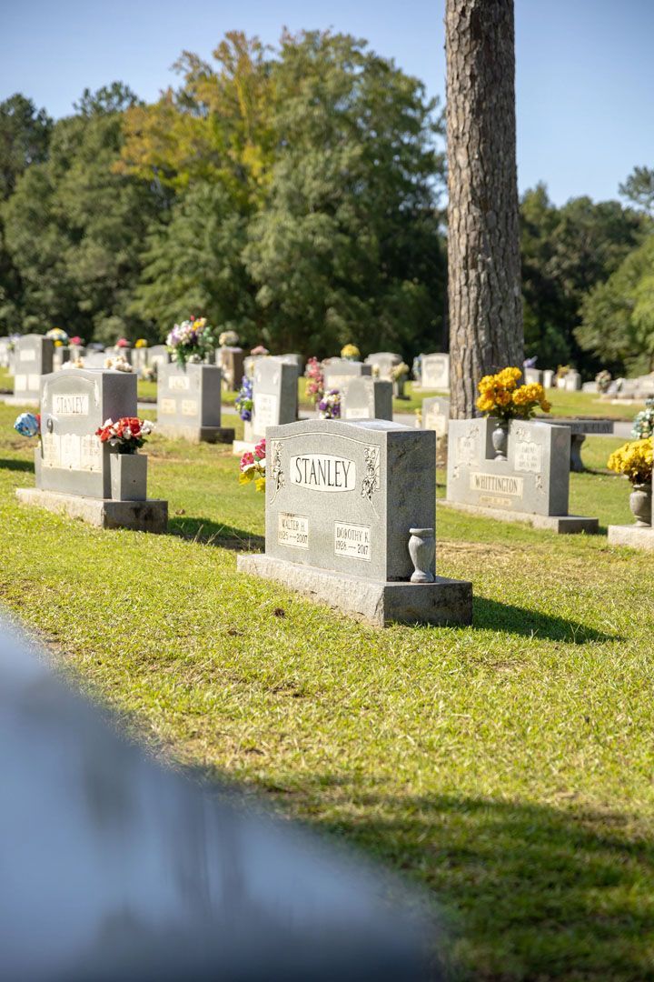 A cemetery with a lot of graves and a tree in the background.