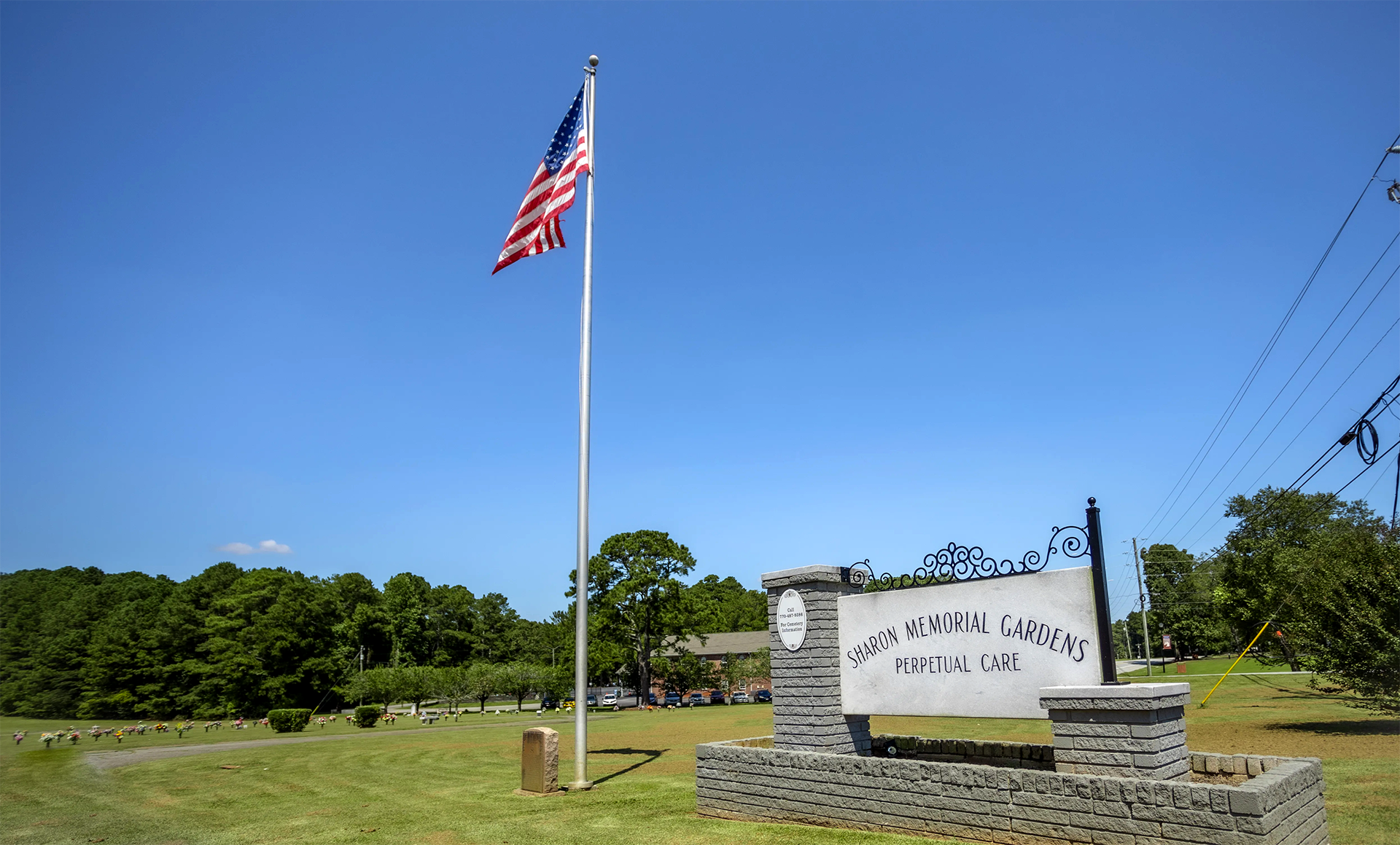 An american flag is flying in front of a sign in a field.