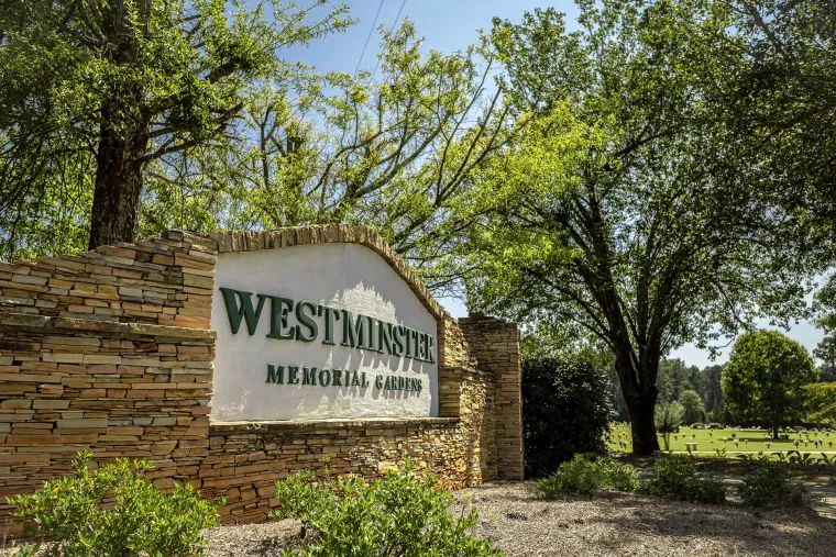 A sign for westhurst memorial park is surrounded by trees