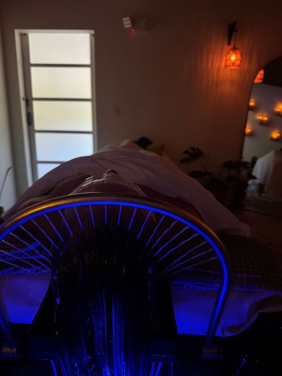 A massage table in a room with a lamp and candles on the wall.