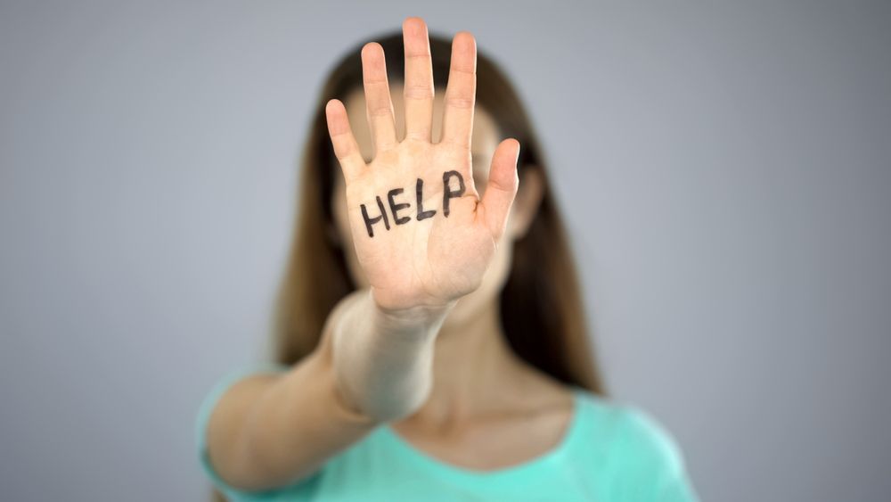A Woman Is Covering Her Face With Her Hand With The Word A Help Written On It — Cairns Criminal Lawyers In Cairns City, QLD